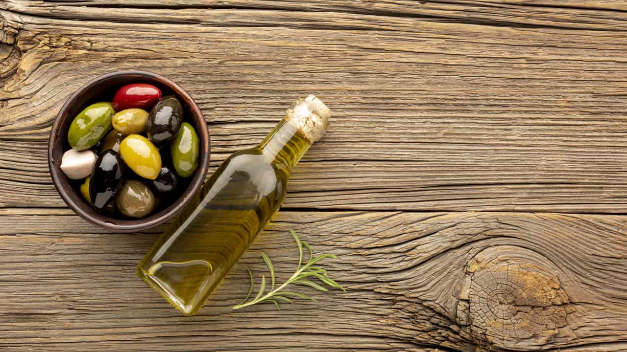 Mesa con variedad de aceite al lado de un cuenco con aceitunas | Aceite Oliva Online